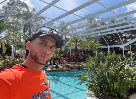 Owner of Swimfinity Elite Pool & Spa Solutions beside a screened pool enclosure