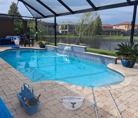 Pool with tiled water feature and cleaning tools on the deck