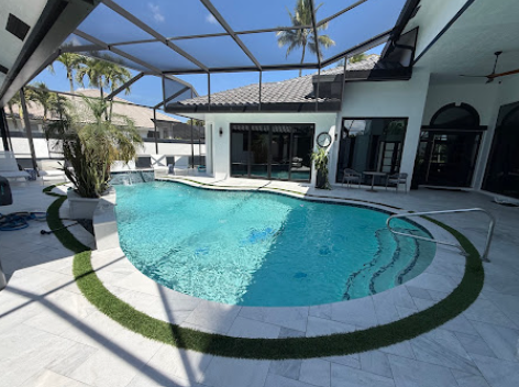 Curved pool with sun shelf surrounded by white stone decking