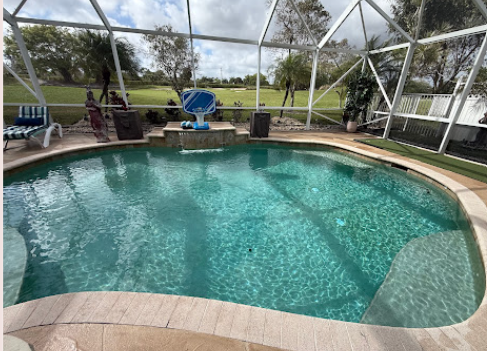 Screened-in pool with clear blue water backing onto a golf course